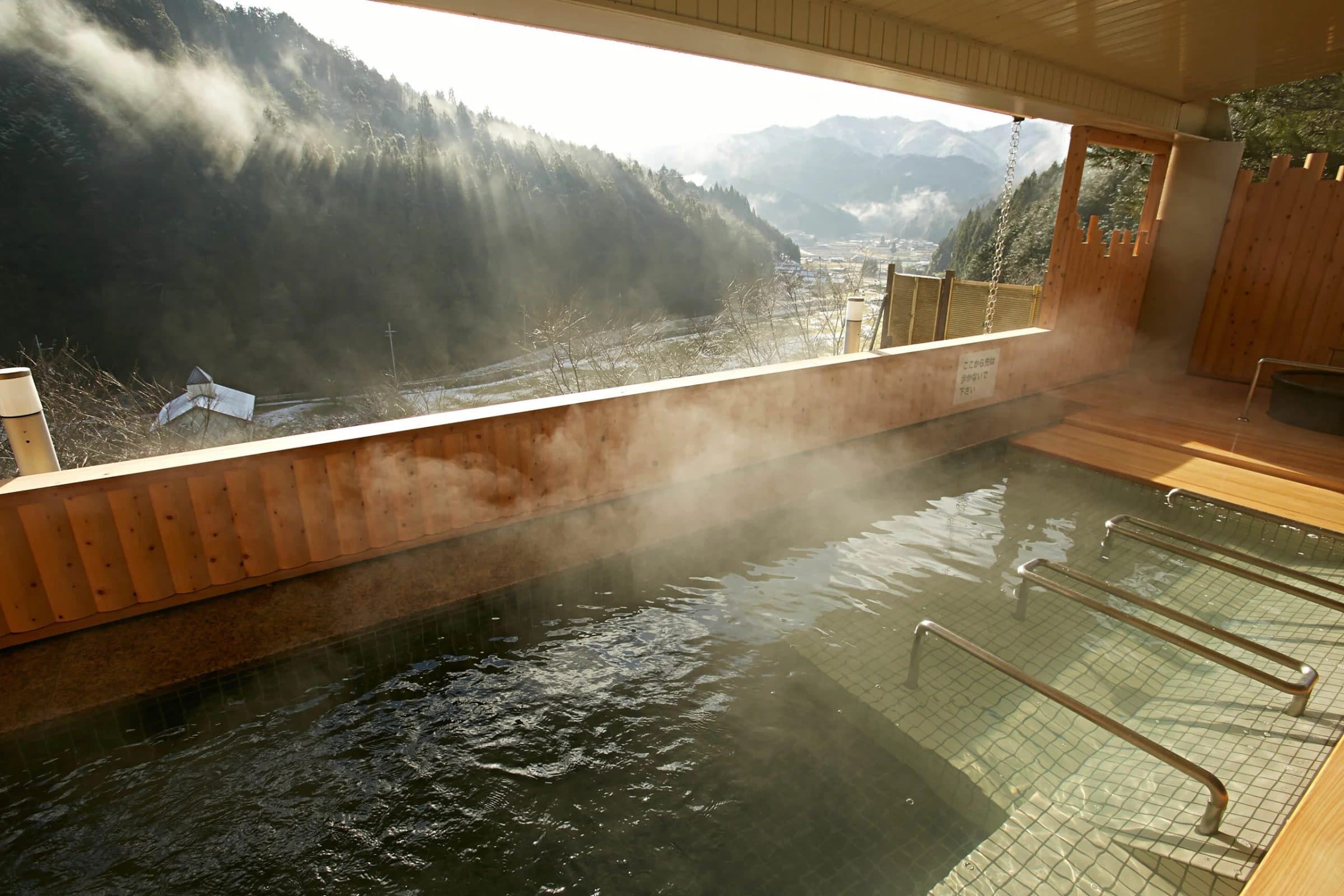 An open-air onsen bath above a mountain valley